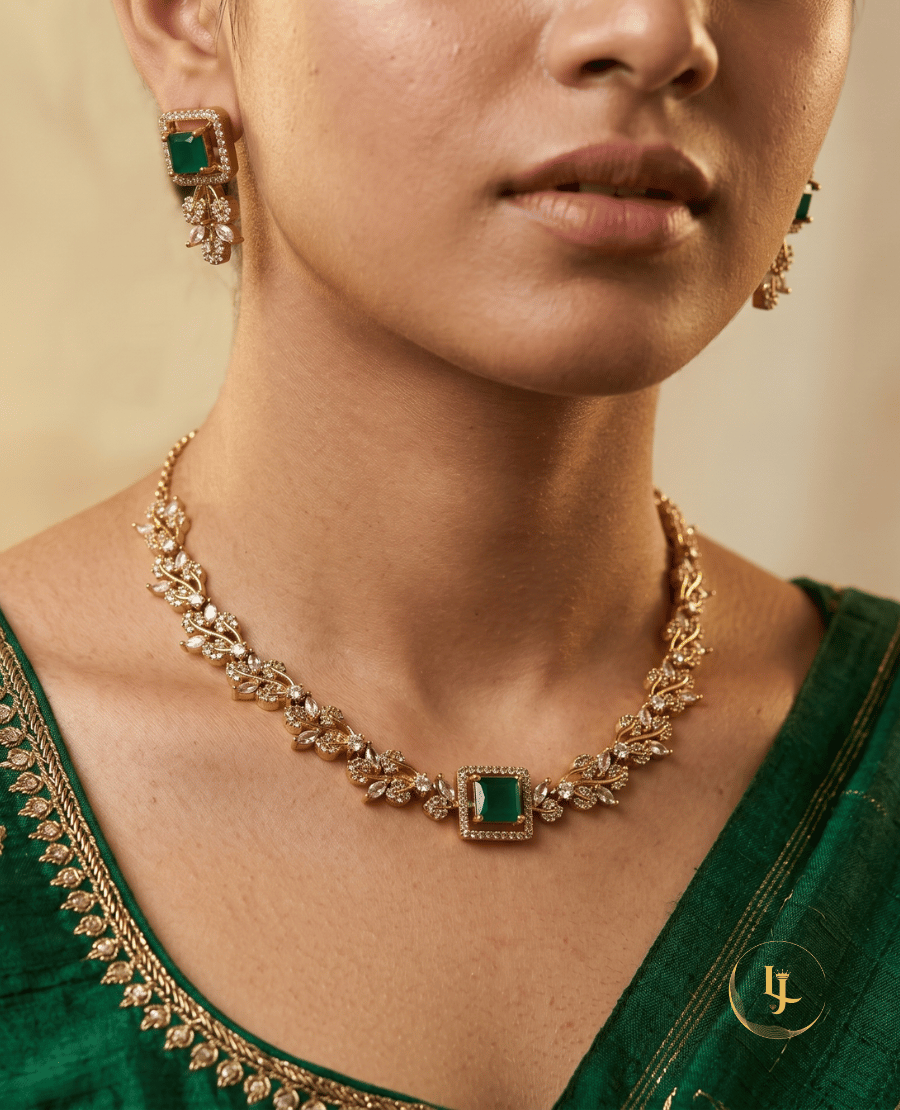 close-up-of-a-model-wearing-landmark-jewels-gold-plated-leaf-choker-and-matching-earrings-with-an-emerald-green-square-gemstone