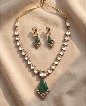 Gold necklace string of triangular Polki crystals with a large dangling green pear-shaped drop pendant, paired with matching earrings.