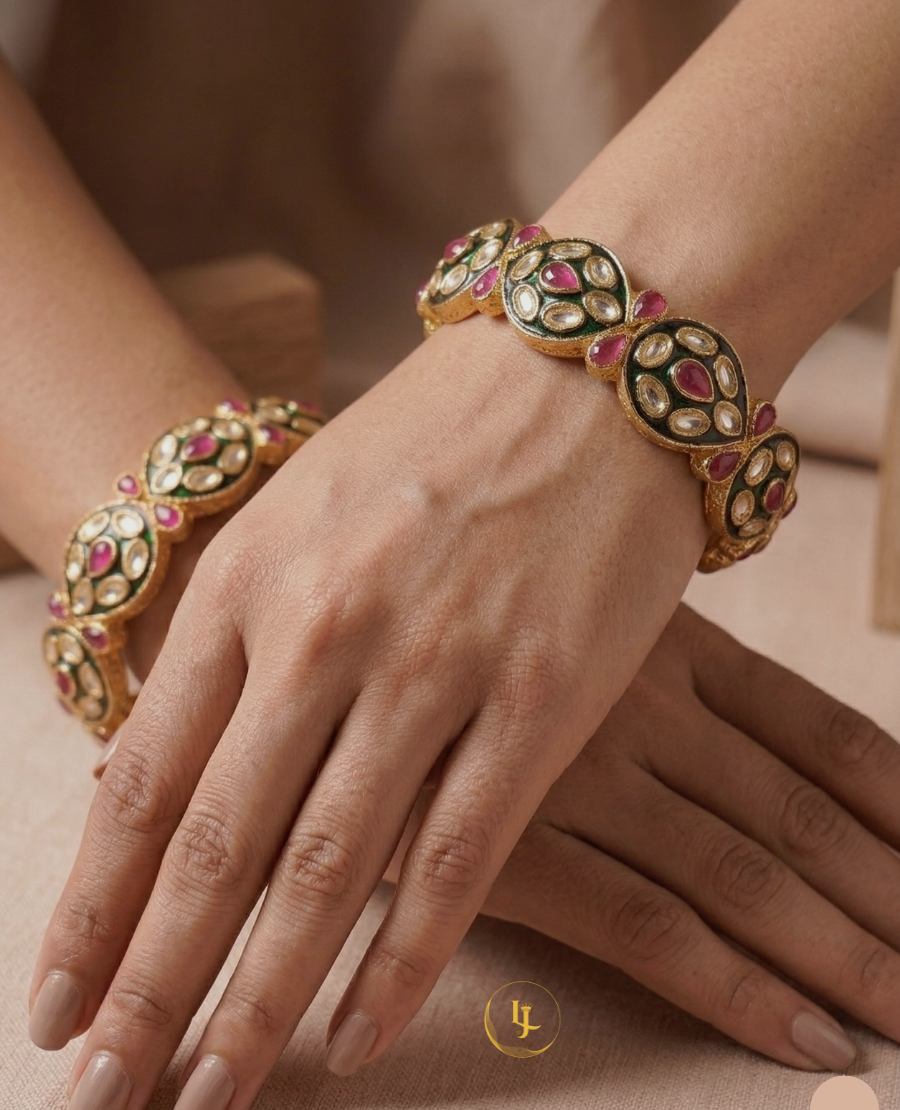 pair-of-gold-plated-indian-bangles-with-ruby-stones-white-polki-crystals-and-black-enamel-work-on-a-floral-background