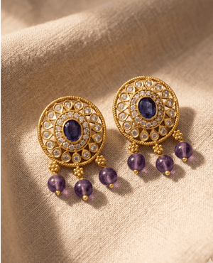Landmark Jewels circular gold-plated earrings featuring an oval blue stone center, crystal halo, and three hanging purple beads.