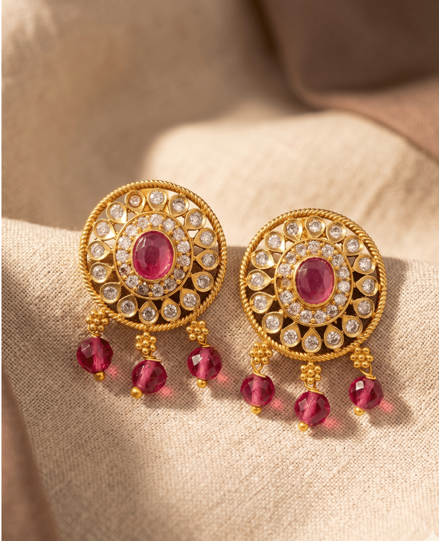 pair-of-round-gold-filigree-earrings-from-landmark-jewels-showcasing-a-ruby-red-oval-centerpiece-and-three-hanging-faceted-pinkish-red-beads