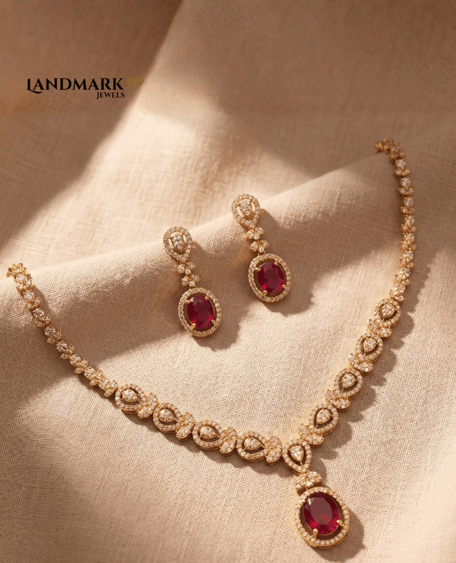 landmark-jewels-gold-plated-necklace-and-earring-set-featuring-oval-red-ruby-stones-and-sparkling-cubic-zirconia-teardrop-accents-on-a-beige-fabric-background