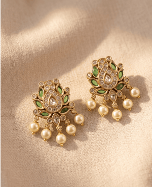 Traditional gold-plated lotus motif earrings accented with green enamel inlay, cubic zirconia, and multiple hanging white pearls.