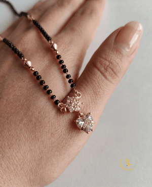 Elegant Landmark Jewels imitation mangalsutra featuring a single string of black beads, gold-textured spacers, and a heart-shaped diamond-look pendant on a neutral linen background.