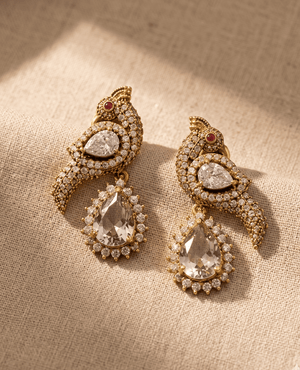 Landmark Jewels gold earrings shaped like birds covered in clear crystal pave, with a large hanging crystal teardrop pendant.