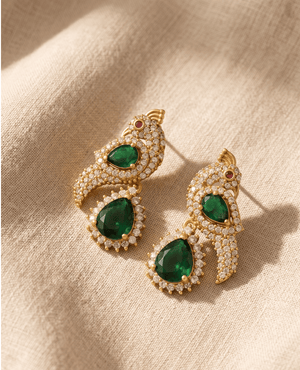 Landmark Jewels gold-plated earrings sculpted like peacocks with white crystals and large teardrop-cut emerald green stones.