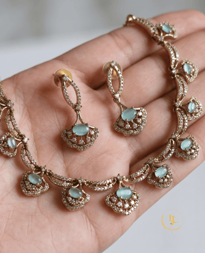 A detailed close-up of the Aura choker and earring set held in hand to showcase the intricate stone placement and rose gold craftsmanship.