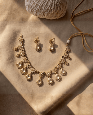 Traditional gold Polki necklace with hanging tear-drop pendants and multicolored gemstone accents, paired with matching earrings and a golden cord