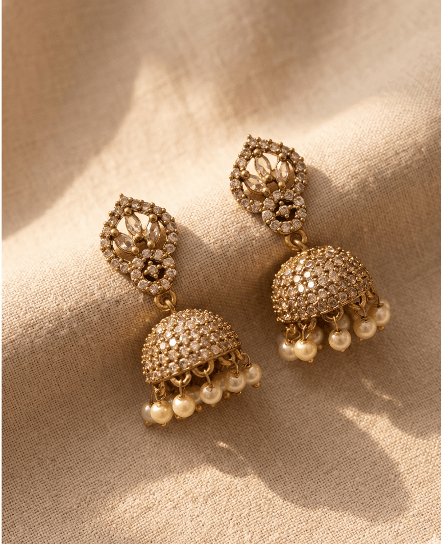 pair-of-traditional-gold-toned-jhumka-earrings-covered-in-clear-crystal-pave-work-with-an-openwork-floral-top-and-hanging-ivory-pearls