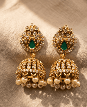 Landmark Jewels gold jhumka earrings featuring an emerald green teardrop stone in a cz frame with hanging white faux pearls.