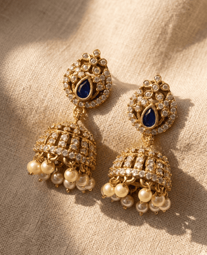 Landmark Jewels traditional Indian jhumka earrings in antique gold featuring a blue stone stud and crystal dome with dangling pearls.
