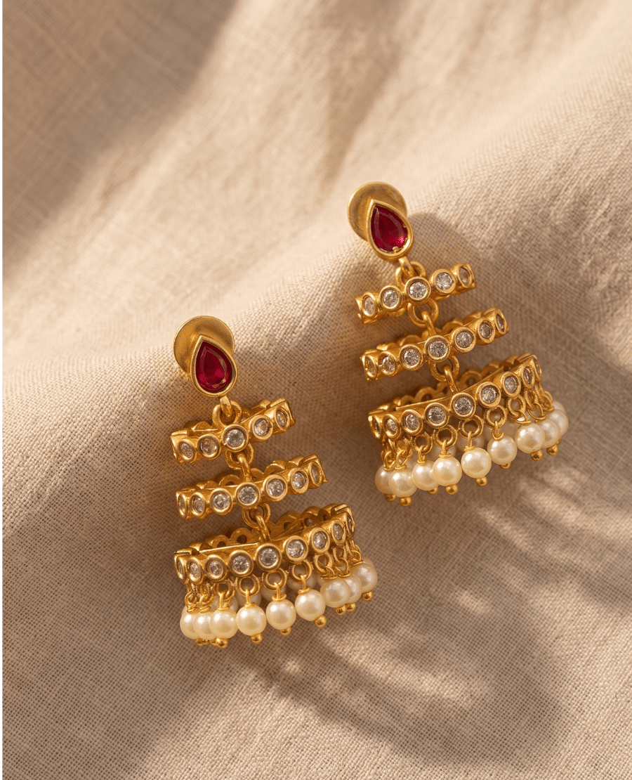 modern-tiered-gold-jhumka-earrings-from-landmark-jewels-with-a-red-teardrop-stone-stud-three-crystal-lined-open-bands-and-hanging-pearl-drops