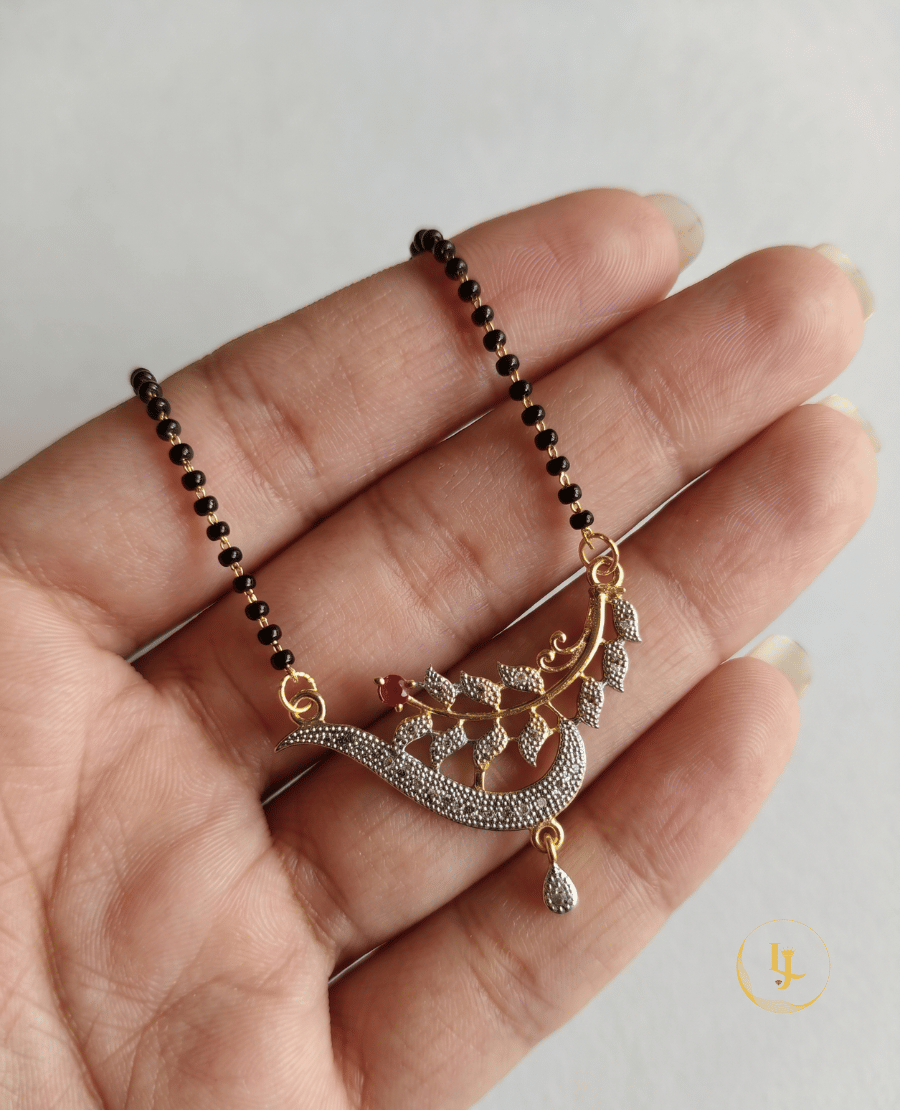 landmark-jewels-imitation-mangalsutra-with-a-single-strand-of-black-beads-and-a-gold-plated-pendant-featuring-a-sparkling-cz-encrusted-leaf-and-vine-design-on-a-cream-fabric-background