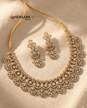 Landmark Jewels mint green and cubic zirconia floral scallop necklace set with matching long drop earrings on a beige fabric background.