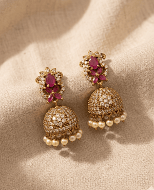 Landmark Jewels classic gold-plated jhumka earrings featuring a pink ruby stone floral top and a crystal-studded dome with hanging pearl drops.