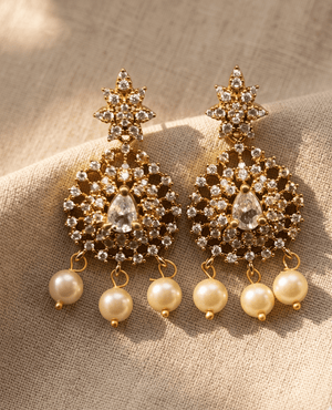 Elaborate gold-plated chandelier earrings with a starburst top, clear cz crystal filigree disc, and cascading white pearl beads.