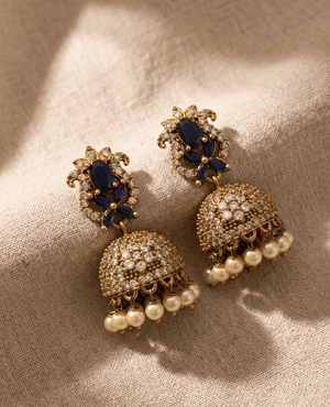 Heavy Indian traditional gold Jhumka earrings with a navy-blue stone paisley top and a crystal-studded dome bell finished with delicate cream hanging pearls.