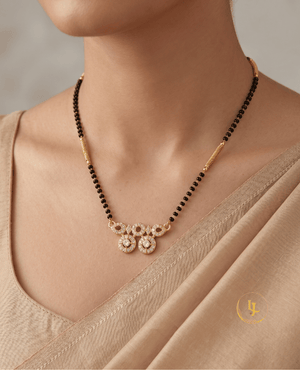 Landmark Jewels modern mangalsutra featuring a single strand of black beads with gold pipe spacers and a geometric gold pendant made of CZ-studded circles on a textured fabric.