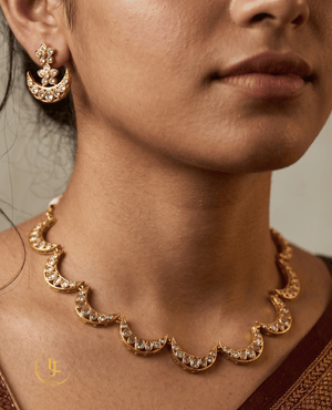 Close-up of a woman wearing a gold-toned crescent moon Kundan necklace and matching earrings.