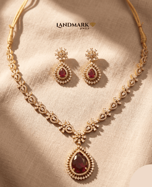 Landmark Jewels ruby red teardrop pendant necklace and matching drop earrings with American Diamond embellishments on a gold-plated floral chain.