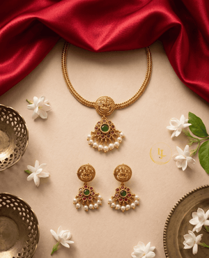 Traditional flat lay of Landmark Jewels temple necklace and earrings set with jasmine flowers and red silk fabric background.