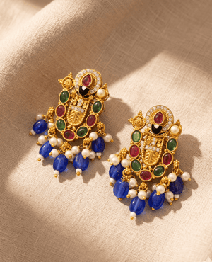 Intricate multi-color imitation gold earrings by Landmark Jewels featuring green, red, and black stonework with hanging royal blue and white bead drops