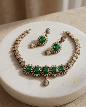 Luxury imitation emerald necklace and earring set by Landmark Jewels displayed on a white marble surface.