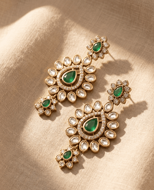 Exquisite gold chandelier earrings featuring vibrant emerald green teardrop stones encircled by clear faceted marquise stones in a tiered design
