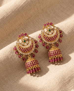 Landmark Jewels antique gold Jhumka earrings featuring a crescent shape packed with square red rubies, a green center stone, and ruby bead hangings.