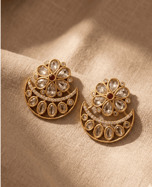Landmark Jewels antique gold stud earrings designed with a Kundan stone flower and an attached crescent moon shape on textured fabric.
