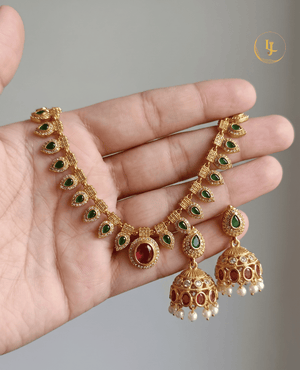 A hand holding the matte gold-plated kemp necklace and earrings set from Landmark Jewels to show scale and detail.