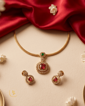 Flat lay view of Landmark Jewels ruby red circular pendant set with gold wheat chain on a cream background.