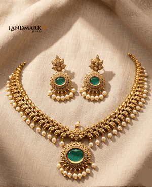 Landmark Jewels antique gold-plated choker necklace and earring set featuring round emerald-green stones, white pearl droplets, and intricate traditional carvings.