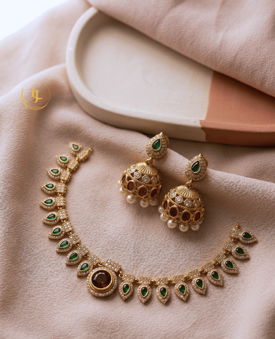 high-angle-flatlay-of-the-prisha-necklace-set-and-jhumkas-on-a-soft-pink-fabric-background-highlighting-the-intricate-stone-work