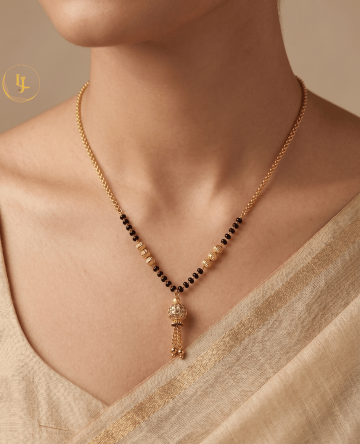 Landmark Jewels modern gold-plated mangalsutra featuring a stone-studded globe pendant with gold tassels and a delicate black bead chain.