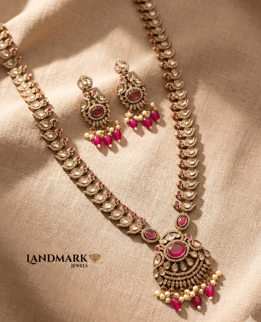 landmark-jewels-traditional-long-gold-toned-necklace-and-earring-set-featuring-ruby-red-stones-white-polki-work-and-pearl-bead-drops-on-a-neutral-fabric-background