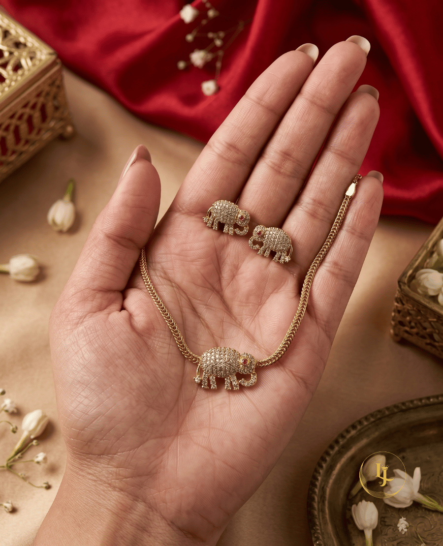 a-hand-holding-a-premium-landmark-jewels-elephant-necklace-and-earring-set-showing-the-delicate-scale-and-sparkling-white-stone-craftsmanship