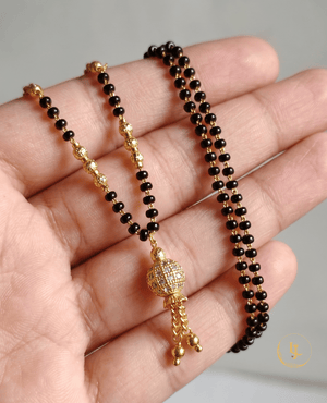 Landmark Jewels modern gold-plated mangalsutra featuring a stone-studded globe pendant with gold tassels and a delicate black bead chain.