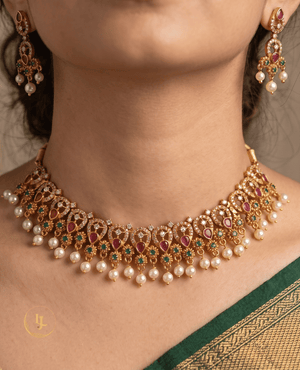 Close-up of a woman wearing Landmark Jewels ruby and emerald gold-plated choker necklace with matching earrings and a green saree.