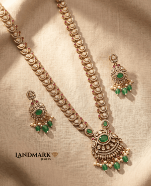 Exquisite antique gold-plated long necklace and earring set featuring white Polki stones, emerald green centerpieces, and pearl hangings by Landmark Jewels.