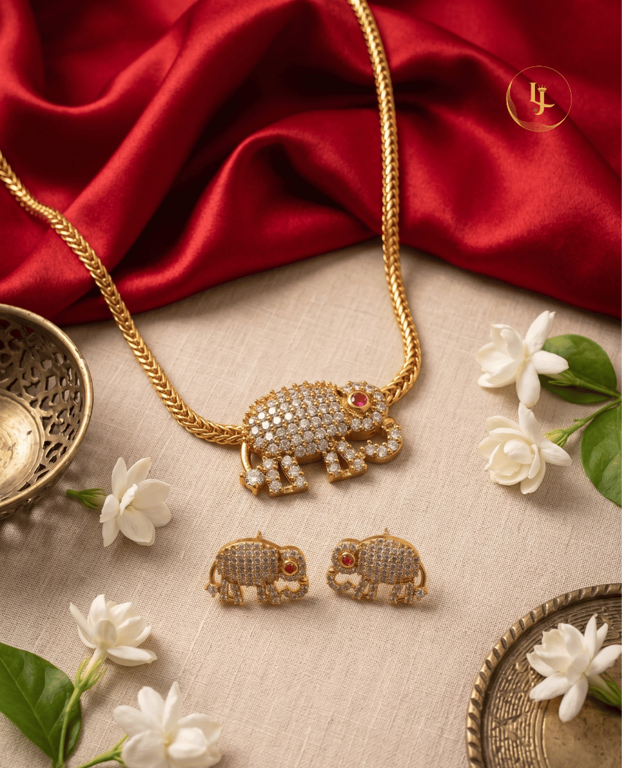 top-down-view-of-landmark-jewels-elephant-jewelry-set-on-a-beige-fabric-background-with-red-silk-and-jasmine-flowers-highlighting-the-ruby-red-eye-detail