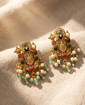 Intricate antique gold-plated temple style earrings adorned with green, red, brown, and white stones and beaded drops.