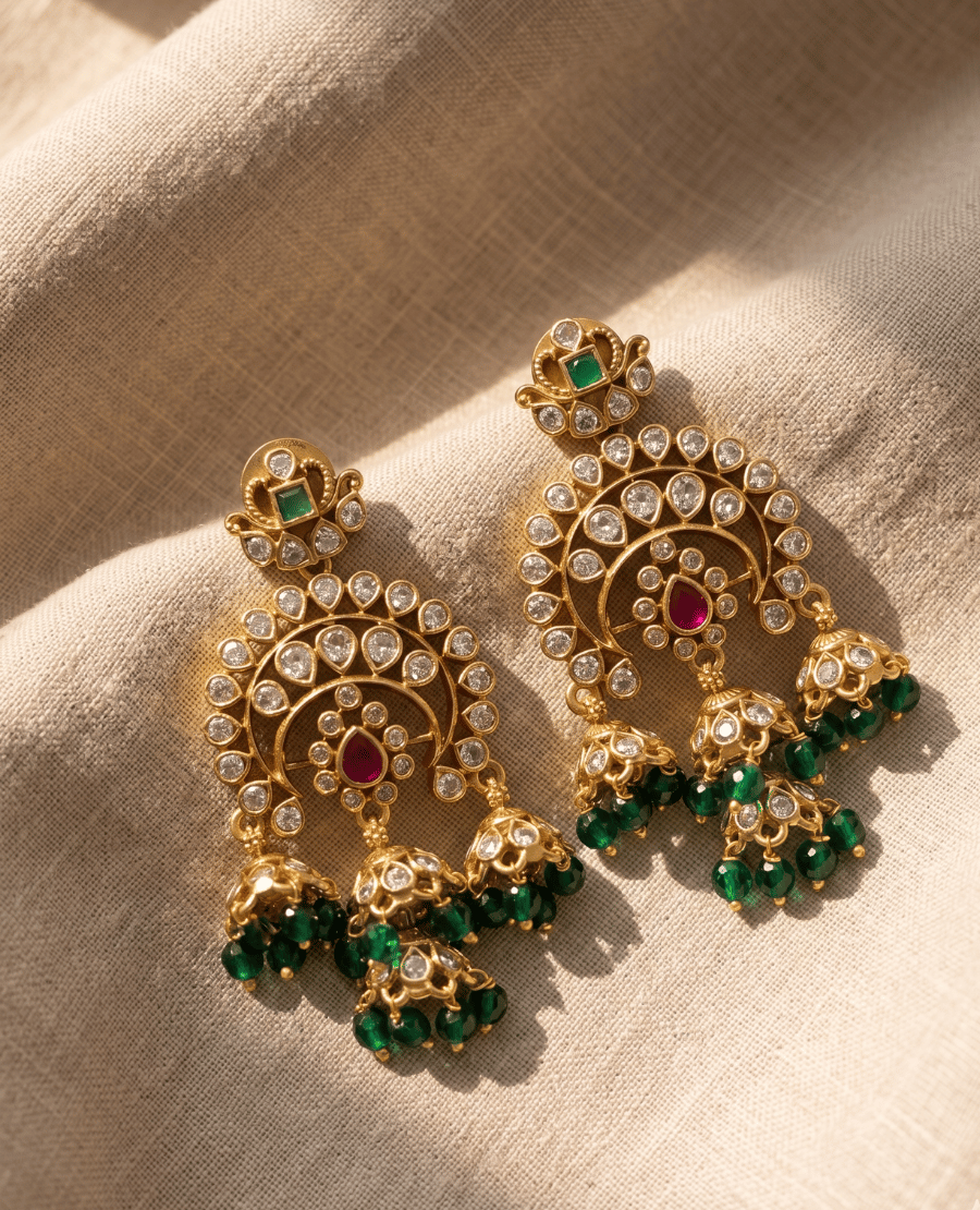 elaborate-gold-kundan-chandbali-earrings-featuring-three-dangling-jhumkas-and-emerald-green-glass-beads