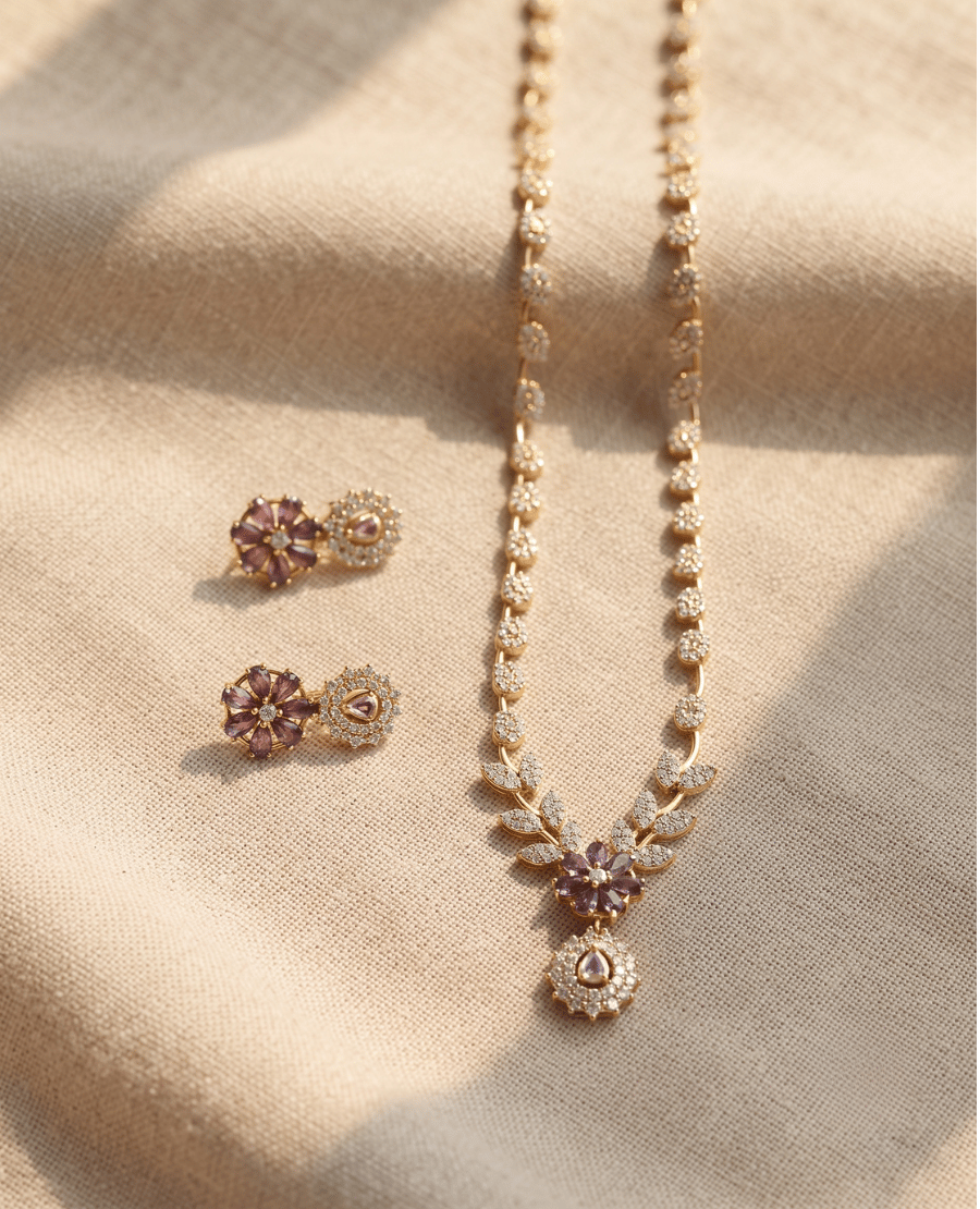gold-chain-necklace-with-a-floral-pendant-and-matching-earrings-featuring-purple-stones-laid-on-textured-cream-cloth