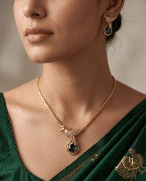 Model showcasing Landmark Jewels emerald green bird motif pendant necklace and matching earrings with a green silk saree.