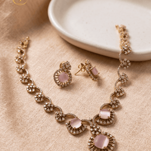 Top-down view of the Landmark Jewels imitation jewelry set featuring pink gemstones and CZ crystals on a beige textured background.