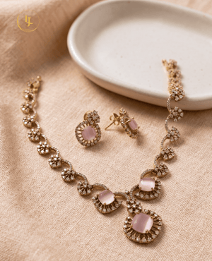 Top-down view of the Landmark Jewels imitation jewelry set featuring pink gemstones and CZ crystals on a beige textured background.
