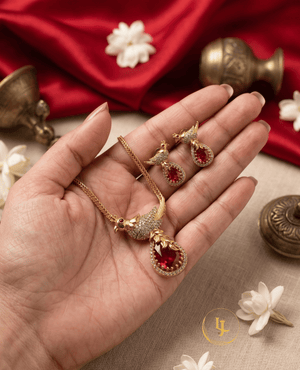 Close-up of Landmark Jewels gold-plated ruby red necklace and earrings in hand.