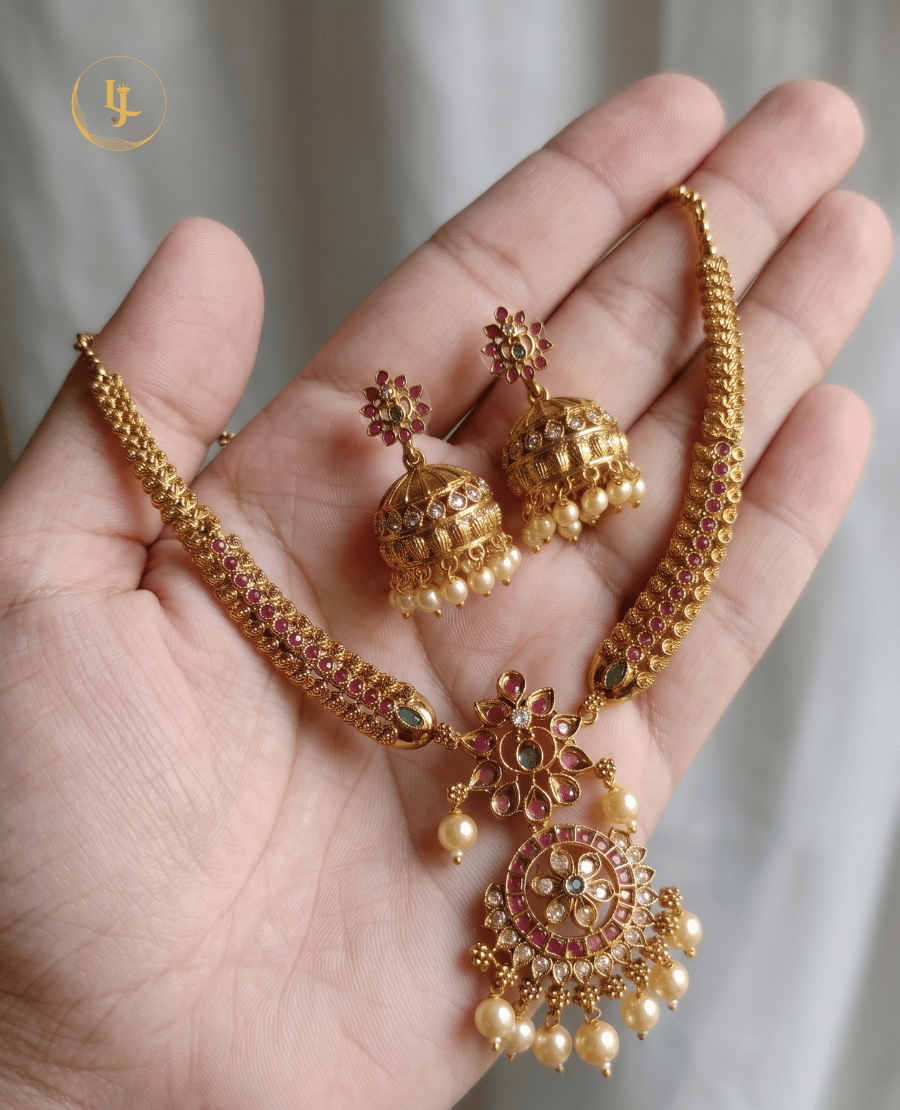 close-up-of-landmark-jewels-ruby-and-emerald-kemp-stone-necklace-and-jhumkas-held-in-hand-to-show-intricate-gold-plated-detail