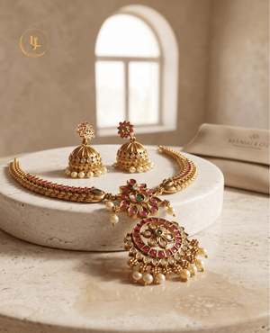 Landmark Jewels temple-style necklace and earring set displayed on a white marble platform for a luxury product view.